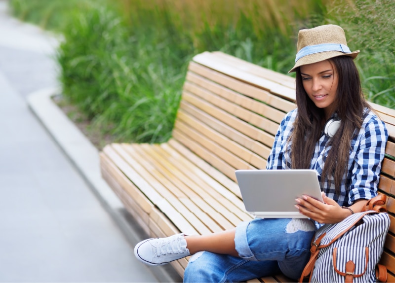 Woman looking at computer on park bench